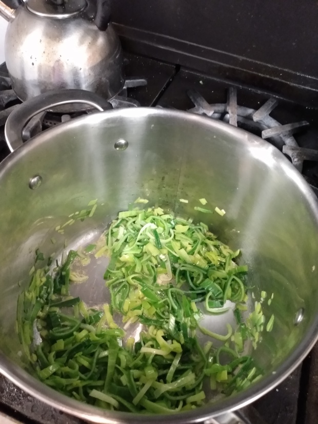 Photo of chopped leek greens cooking in a soup pot.